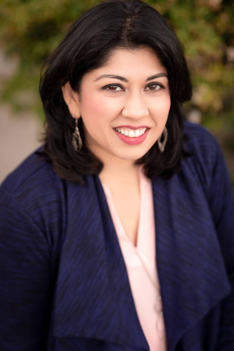 Headshot of Dr. Sarah Rizvi, sitting down, staring at the camera