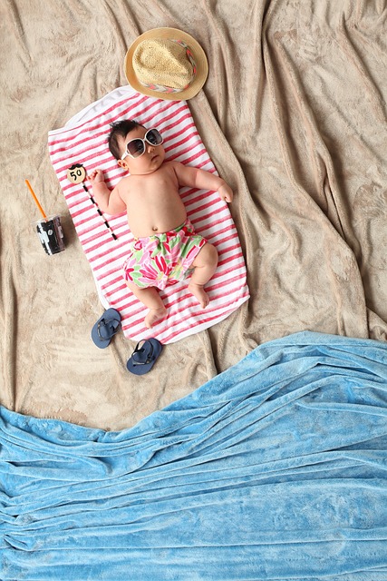 fat baby, wearing sunglasses, lying on a beach towel on the beach