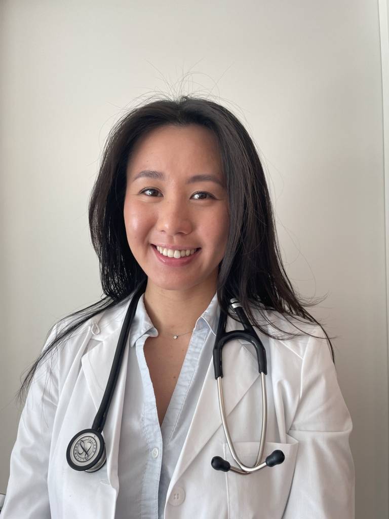 Angel Wong, PA, looking at the camera, smiling. Shoulder length black hair. She is wearing a white coat and has a stethoscope around her neck.