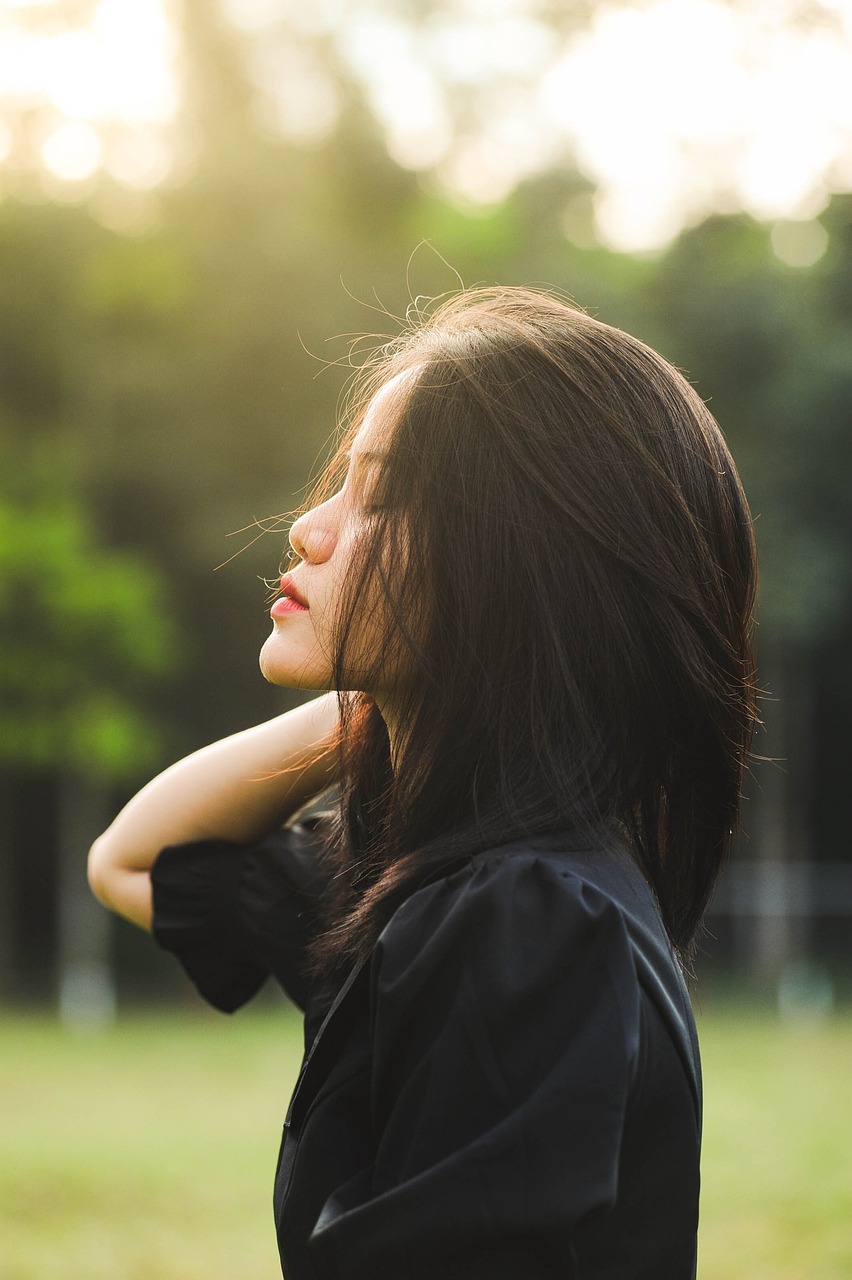 Image of a woman facing left, shoulder length straight black hair with an expression of overwhelm, head tilted up to the sky