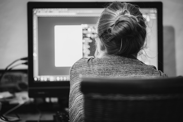 black and white photo of the back of a woman's head staring at a computer screen